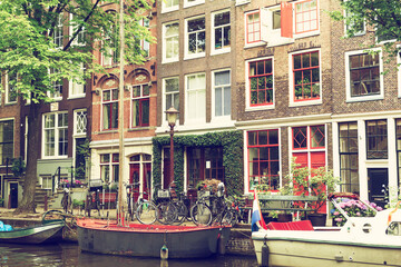 Fototapeta na wymiar Traditional Dutch houses standing on the bank of the canal. Amsterdam. Netherlands. Photo is edited and with an vintage photo.