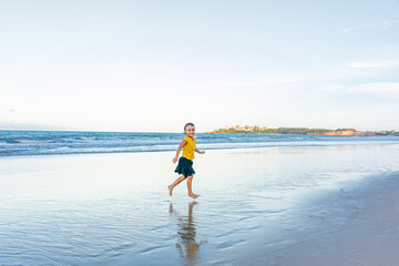 Child dancing cheerfully on the beach with shadows