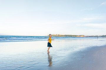 Child dancing cheerfully on the beach with shadows