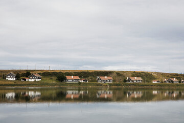 Fototapeta premium Houses in Beagle Channel sea coast, and their perfect reflection in water. Cityscape, Ushuaia.