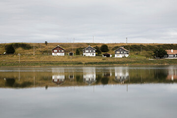 Fototapeta na wymiar Houses in the Beagle's Channel ocean coastline and their reflection in sea water, in Ushuaia, Tierra del Fuego, Argentina.