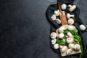 Obraz na płótnie Canvas fresh mushrooms champignon on a wooden cutting Board. Black background. Top view. Space for text