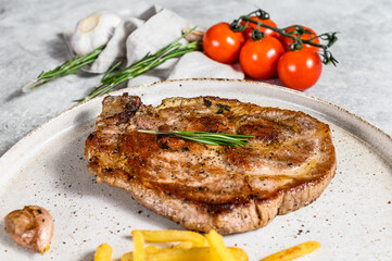 Pork steak with French fries. Grilled meat. Gray background. Top view.