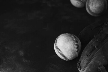 old baseball glove and ball flat lay on black background.