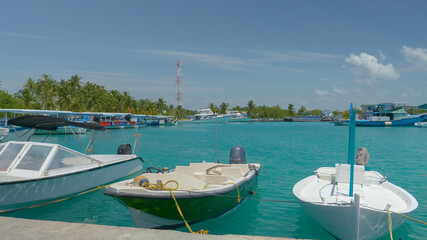 Fototapeta na wymiar Locals' boats fill up the turquoise docks on a quiet tropical island in Asia.