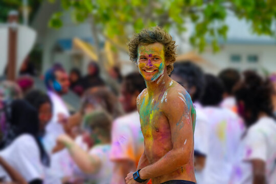 CLOSE UP: Shirtless tourist man covered in paint parties at holi festival.
