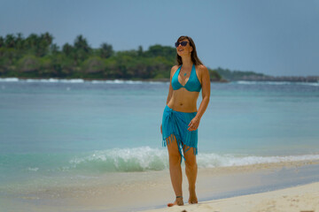 CLOSE UP: Carefree woman in a bikini strolls along the idyllic white sand beach.