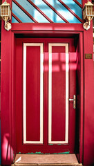 Bright red door with white inserts in the English style. Lamps above the door
