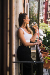 Woman enjoying spring with her wine on the balcony.