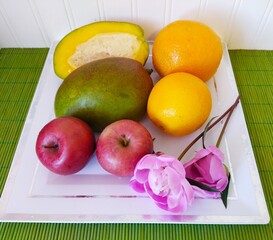 still life of fruit oranges mango and apples and peony flowers on a white plate