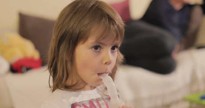 Beautiful little girl inhaling herself with a nebulizer