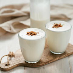 Kefir, buttermilk or yogurt with granola. Yogurt in glass on white wooden background. Probiotic...