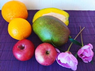 Still life of  fruits oranges mango apples and peony flowers on a table