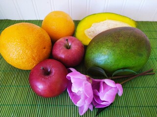 Still life of fruit red apples oranges green cut mango peony flowers on the table