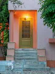 vintage family house entrance stairs and decorated door with foliag, lights on