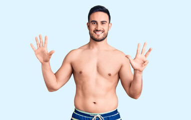 Fototapeta premium Young handsome man wearing swimwear showing and pointing up with fingers number nine while smiling confident and happy.