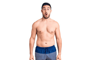 Fototapeta premium Young handsome man wearing swimwear scared and amazed with open mouth for surprise, disbelief face