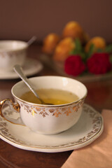 Luxury snack, with two cups with infusion, some muffins and some flowers on the table