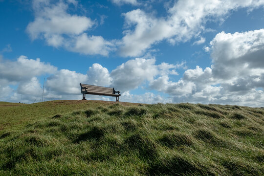 Bench on a hill with blue sky and clouds 