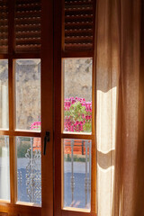 The morning sun passes through the transparent curtains of the window, flowers are outside the window. Soft focus