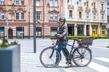 Fototapeta na wymiar young woman pushing her e-bike on pedestrian walkway