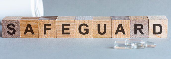 SAFEGUARD text on wooden table for your desing, coronavirus concept top view. Grey background. Safeguard word written on wood block, concept.