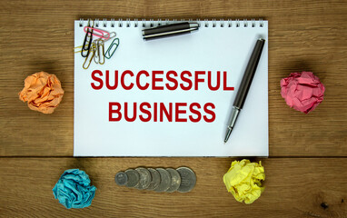 White note with inscription 'successful business' on beautiful wooden table, colored paper, metalic pen. Business concept.