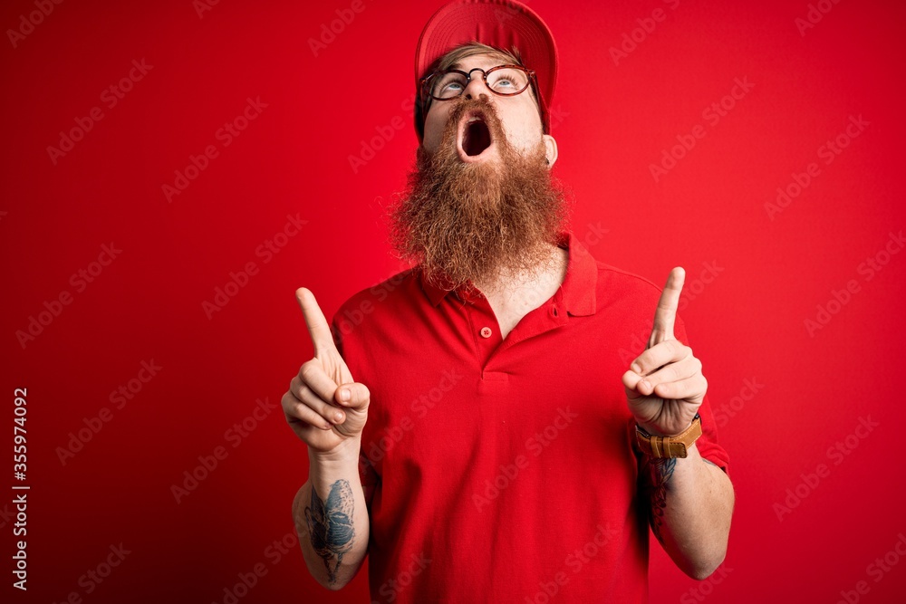 Poster young handsome delivery man wearing glasses and red cap over isolated background amazed and surprise