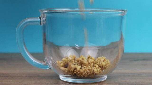 pour milk in cereals with nuts and chocolate in a glass cup