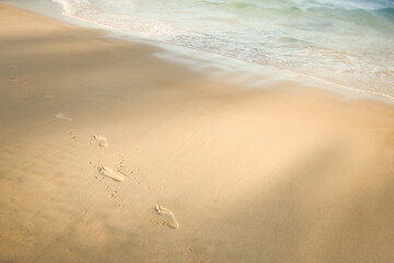 Fototapeta na wymiar Footprints in sand on sea coast. Print barefoot on beach, side view.