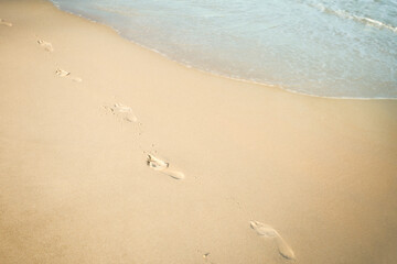 Footprints in sand on sea coast. Print barefoot on beach side view. Close up