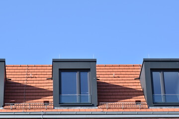 Red roof tiles and dark windows against a blue sky