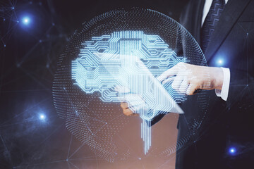 Double exposure of man's hand holding and using a digital device and brain hologram drawing. Data...