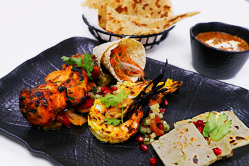 tandoori platter with chicken tikka, grilled prawns, and paneer along with dal makhani, wheat bread and chutneys, Indian food speciality