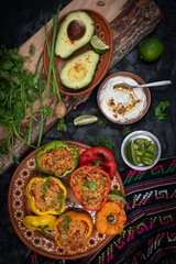Vegetarian rice stuffed peppers along with side dishes in a traditional Mexican setting