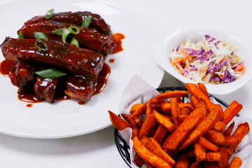 pork baby ribs glazed with barbecue sauce, with sweet potato fries and coleslow salad