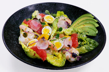 salad with avocado and shrimps in bowl, top view, copy space, black background.