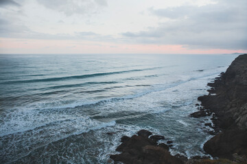 sunrise above the dark atlantic ocean and the black cliff