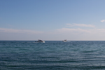 Two white boats navigating towards each other in the sea on a summer day