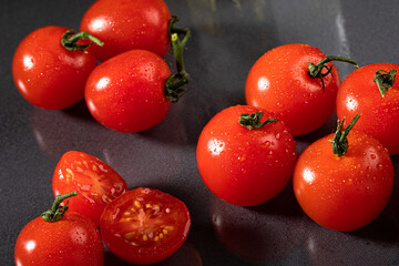 A portion of tasteful red tomatoes on a dark background. Fresh, delicious and red tomatoes, with drops of water on a dark background.