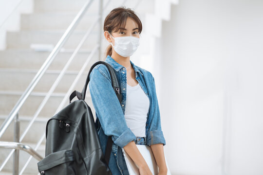 Young student woman wear face mask carry backpack laptop in university
