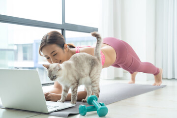 Woman train fitness at home with cat watch online tutorial on laptop
