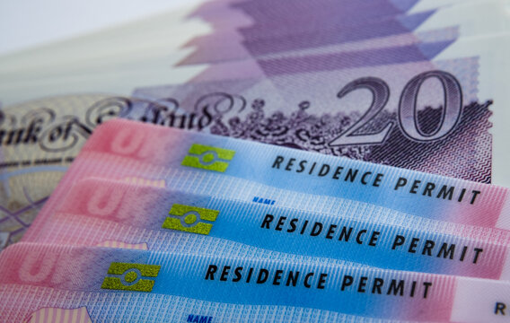UK Biometric Residence permit cards and 20 pound banknotes. BRP cards released for Tier 2 work visa immigrants. Concept image for price of the visa.
