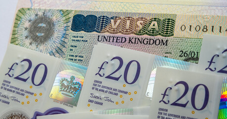 UK entry business and tourist visa in passport and pile of 20 pound banknotes. Concept image for...