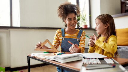 Preparing for school. Caucasian little girl spending time with african american baby sitter. They...