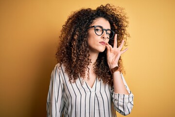 Young beautiful woman with curly hair and piercing wearing striped shirt and glasses mouth and lips...