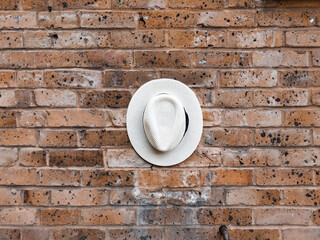 White hat with black detail on a red brick wall