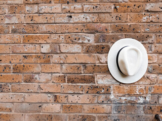 White hat with black detail on a red brick wall
