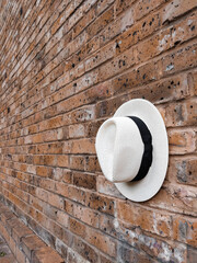 White hat with black detail on a red brick wall