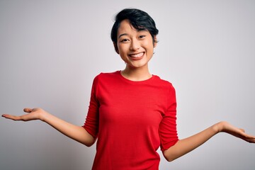 Young beautiful asian girl wearing casual red t-shirt standing over isolated white background smiling showing both hands open palms, presenting and advertising comparison and balance